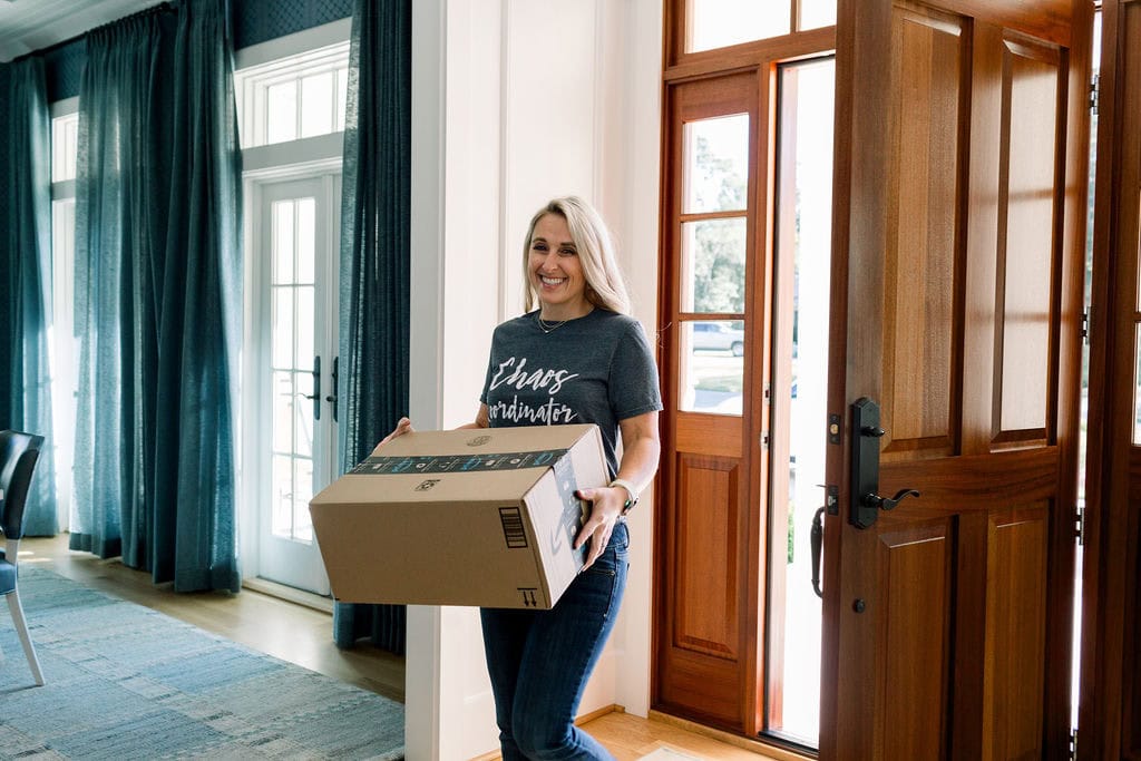 Woman with a moving box walking in the front door of a home